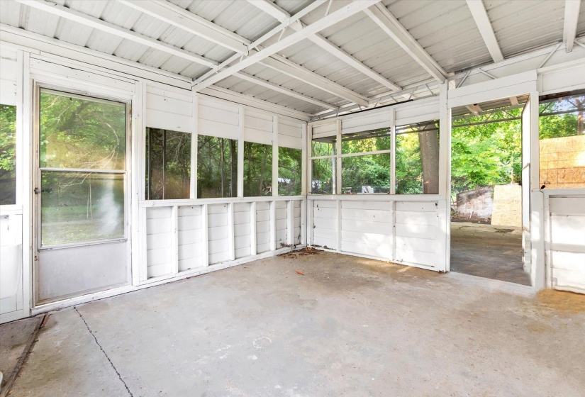 Screened porch featuring a concrete floor, painted wood paneling, and a metal roof structure