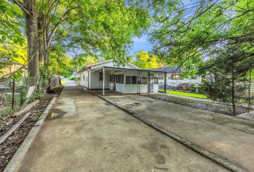 Expansive concrete driveway extending to a white single-story exterior with a covered porch and screened-in area