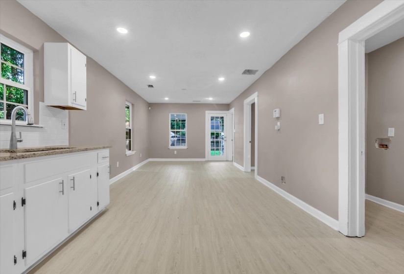 Open-concept living space with light wood-finish flooring, recessed lighting, and neutral wall paint