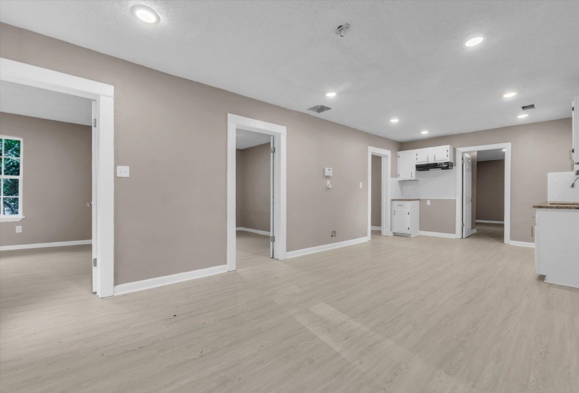 Open-concept living area with light wood-finish flooring, recessed lighting, neutral paint, and white trim