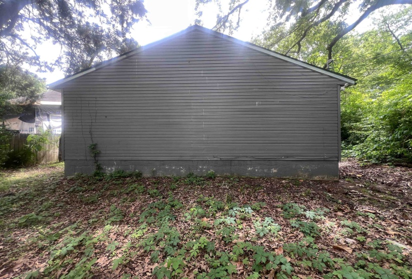 Side elevation of a structure featuring horizontal siding and a visible foundation