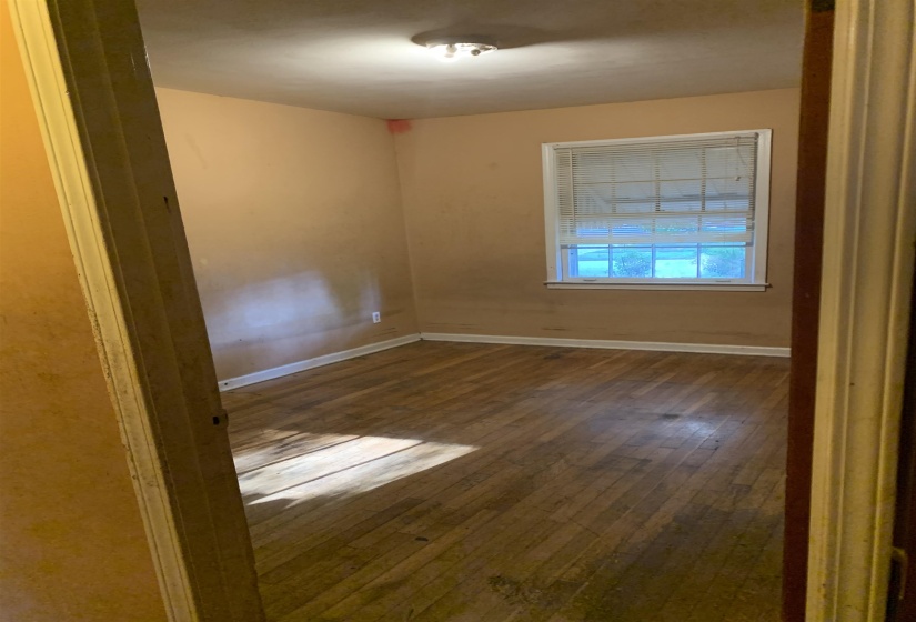Hardwood flooring and a single window with blinds define this interior space