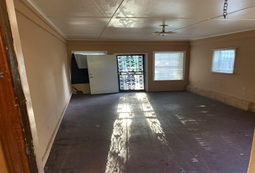 Room featuring a ceiling-mounted light fixture, multiple windows, and a door with an ornate security screen