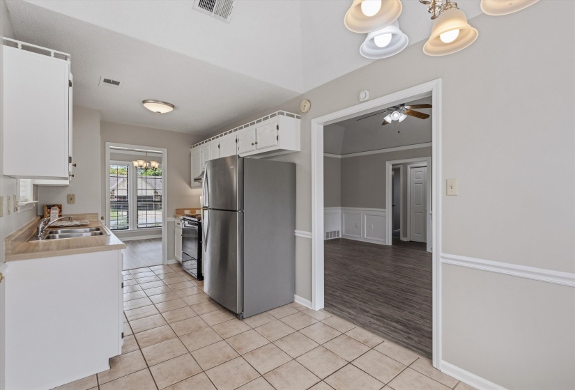 Kitchen with tile flooring, white cabinetry, light countertops, and a double-basin stainless steel sink