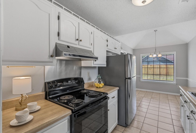 Kitchen featuring white cabinetry, light wood-finish countertops, and a black electric range with an overhead vent