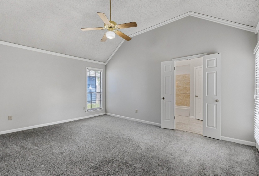 Spacious room featuring vaulted ceilings, a ceiling fan with integrated lighting, and neutral-toned carpeting