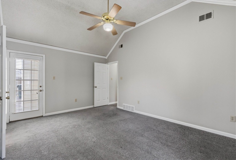 Spacious room featuring vaulted ceilings, a ceiling fan, and grey carpet flooring