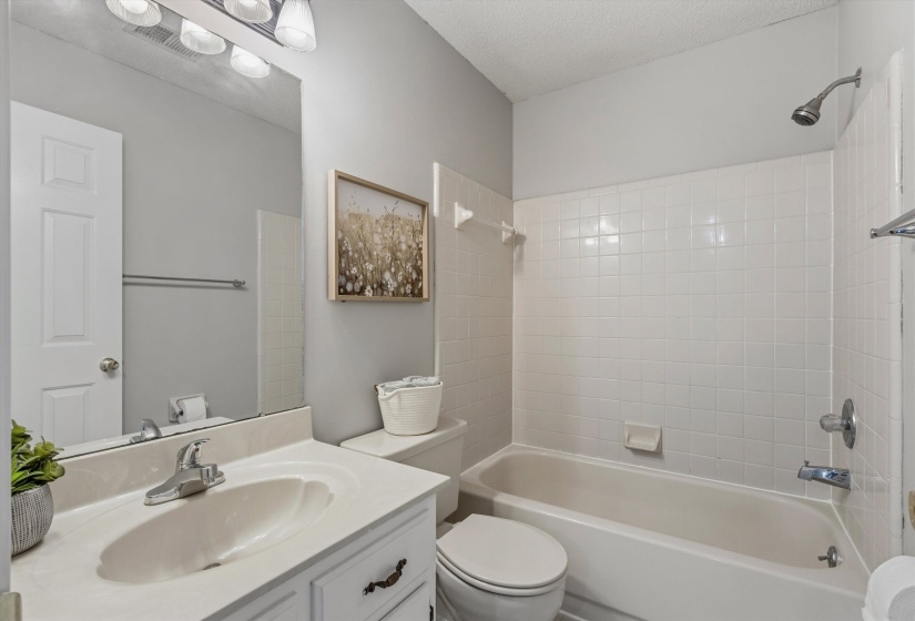 Bathroom featuring a white vanity with an integrated sink, chrome faucet, and a large wall-mounted mirror