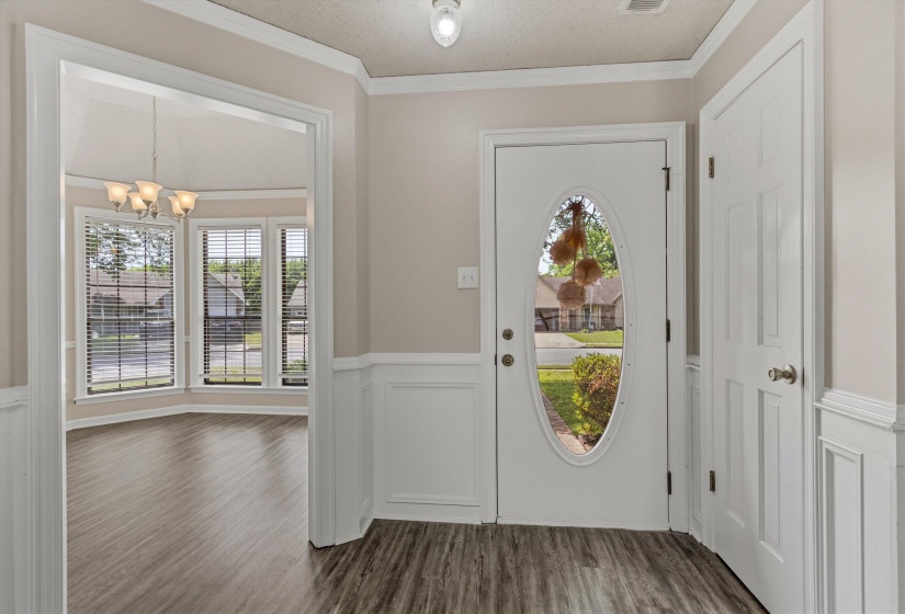 Entryway featuring wood-finish flooring, wainscoting, and crown molding