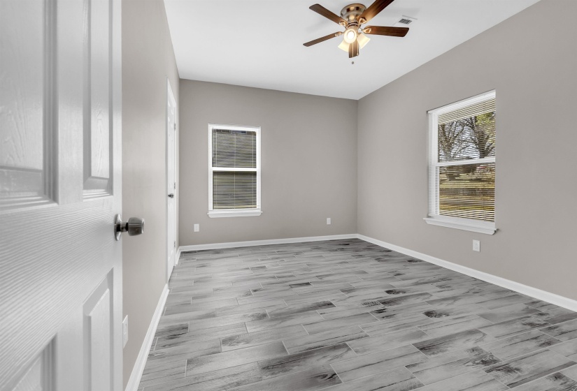 Spacious room featuring gray wood-finish flooring, light gray walls, and white trim