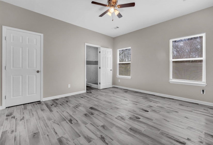 Expansive room featuring wood-finish plank flooring, neutral wall tones, and two windows