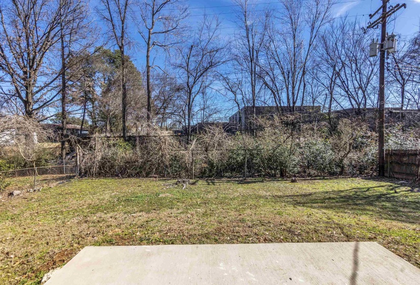 Expansive grass area featuring a concrete pad and chain-link fencing