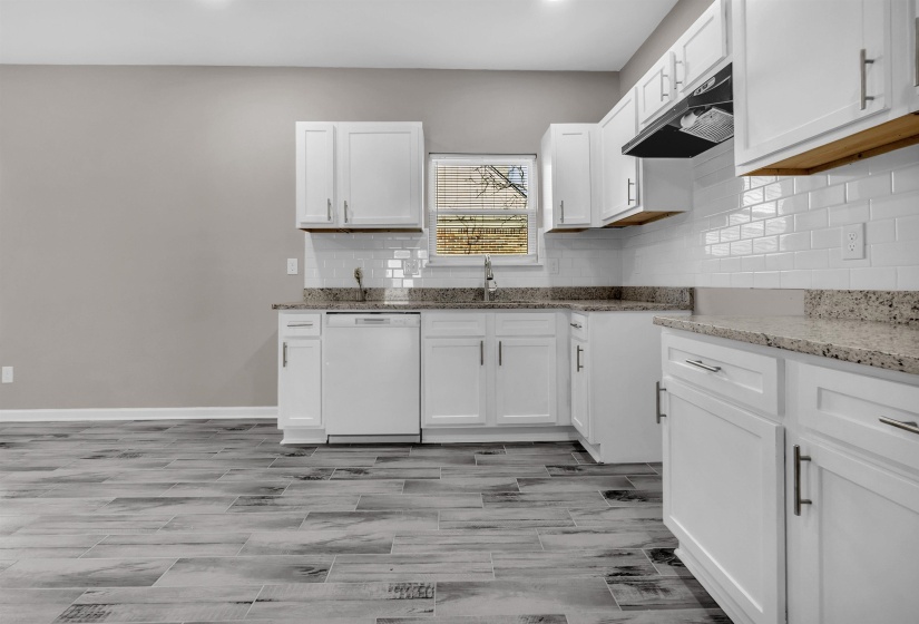 Kitchen featuring white cabinetry, granite-style countertops, subway tile backsplash, and wood-finish flooring