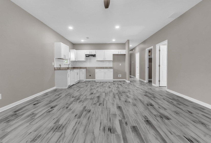 Open-concept living space featuring wood-finish flooring, recessed lighting, and a neutral color palette