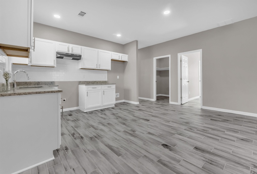 Kitchen featuring white shaker-style cabinetry, granite countertops, subway tile backsplash, and stainless steel sink with a gooseneck faucet
