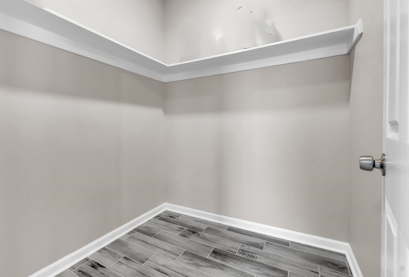 Neutral-toned interior featuring wood-finish tile flooring and crisp white baseboards