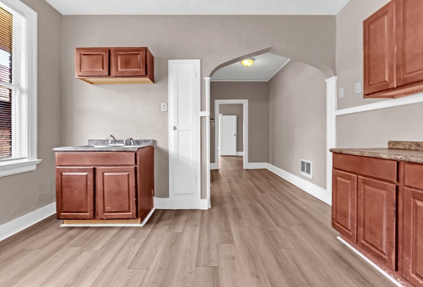 Kitchenette featuring wood-finish flooring, ample cabinetry, and a countertop with an integrated sink