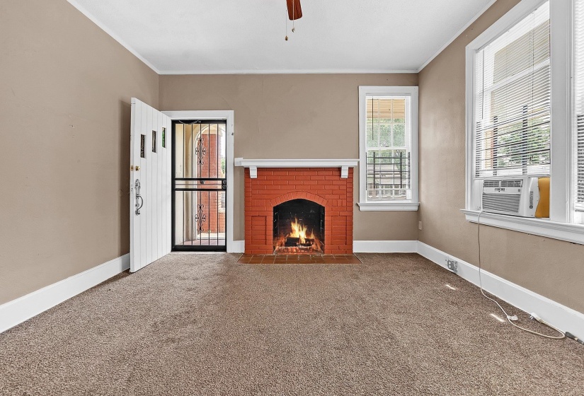 Room featuring a brick fireplace with a white mantel, neutral carpeting, and a white entry door with security screen