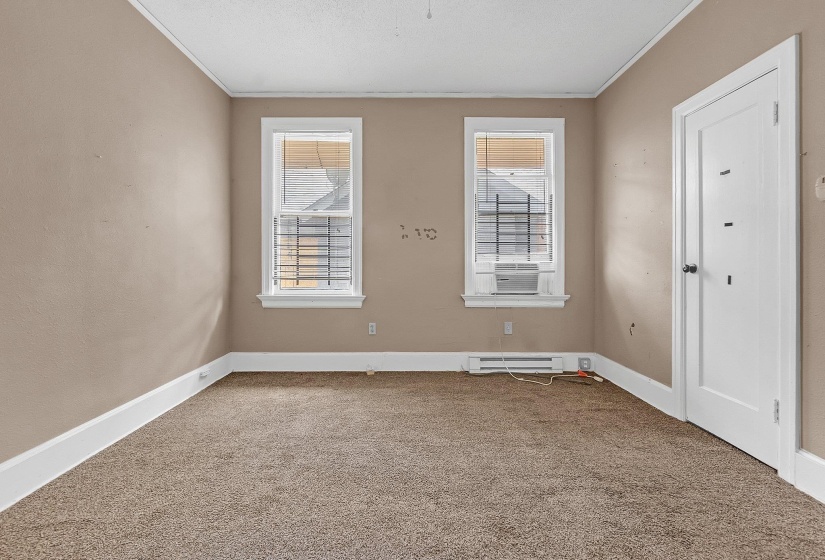 Neutral-toned room featuring two windows with white trim, a textured ceiling, and light brown carpeting