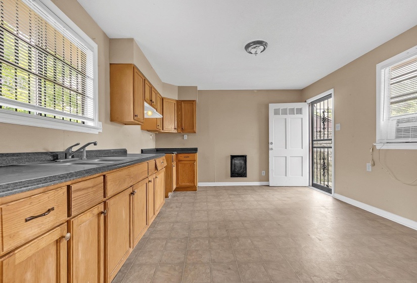 Kitchen area featuring wood cabinetry, dark countertops, and a double basin sink