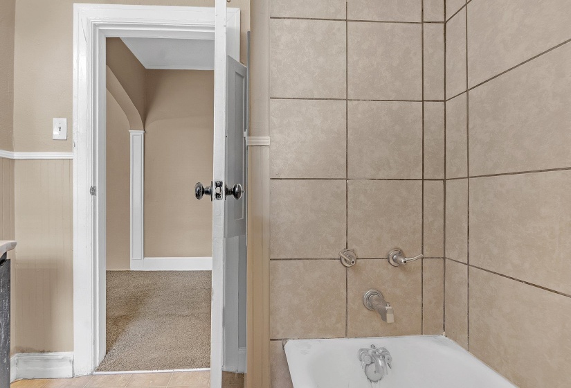 Tile-surround bathtub with chrome fixtures and light-toned wall tiling