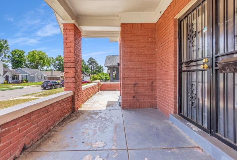 Brick facade with a covered porch featuring a security screen door and a matching brick half-wall