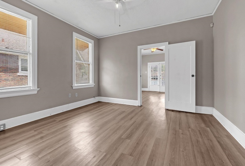 Open-concept living space featuring wood-finish flooring, neutral wall tones, white trim, and two large windows