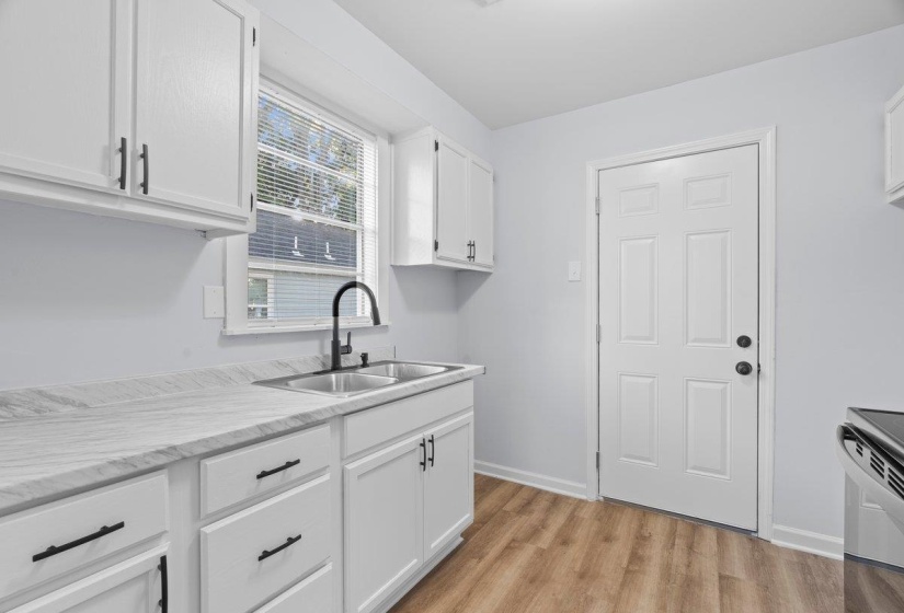 Kitchen featuring white cabinetry with matte black hardware, a stainless steel double basin sink with a matte black high-arch faucet, and wood-finish flooring