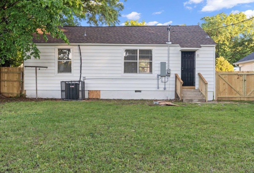 Rear exterior featuring white horizontal siding, a dark pitched roof, and multiple windows