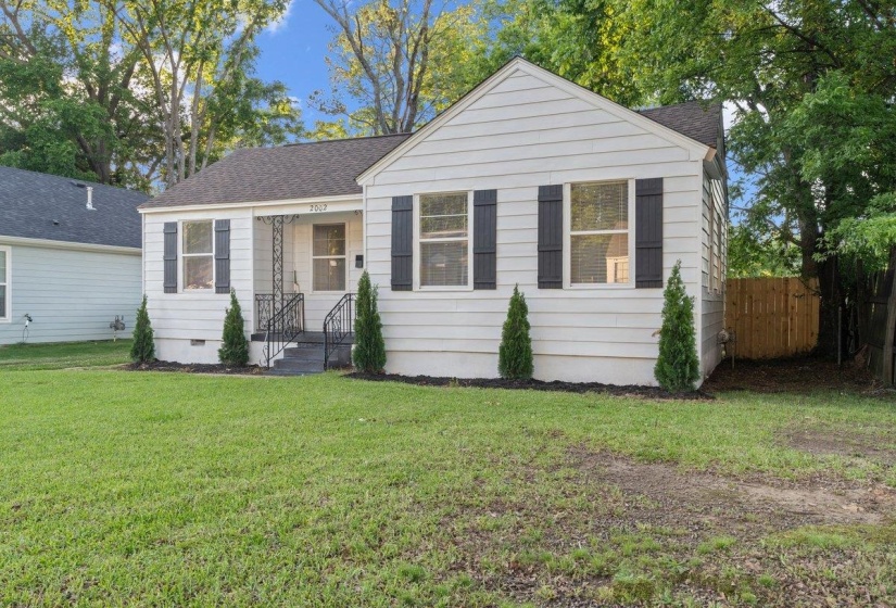 Gable roofline home featuring light-colored siding, dark shutters, and a front porch with wrought iron railings