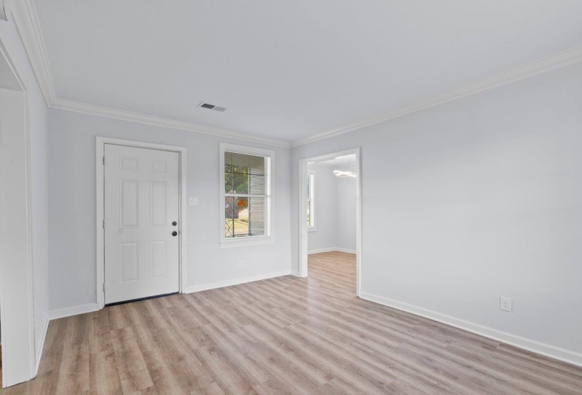 Bright living area featuring wood-finish flooring, white trim, and a panel-style entry door