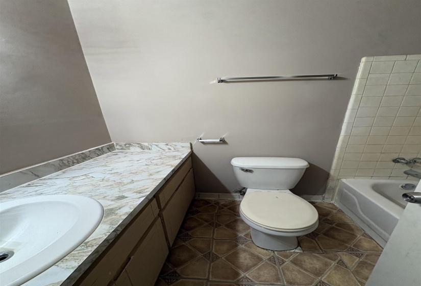 Bathroom featuring a white toilet, built-in vanity with a white basin sink, and a patterned countertop