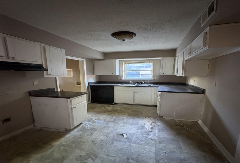 Kitchen featuring white cabinetry, dark countertops, built-in dishwasher, and a window above the sink