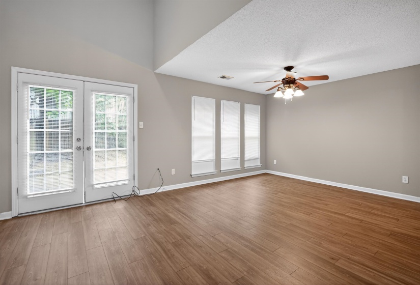 Spacious living area featuring vaulted ceilings, wood-finish flooring, and a ceiling fan with integrated lighting