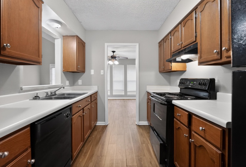 Galley kitchen featuring wood-finish cabinetry, white countertops, and wood-look flooring
