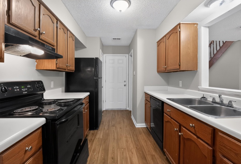 Kitchen featuring wood-finish cabinetry, white countertops, and black appliances including a range, refrigerator, and dishwasher