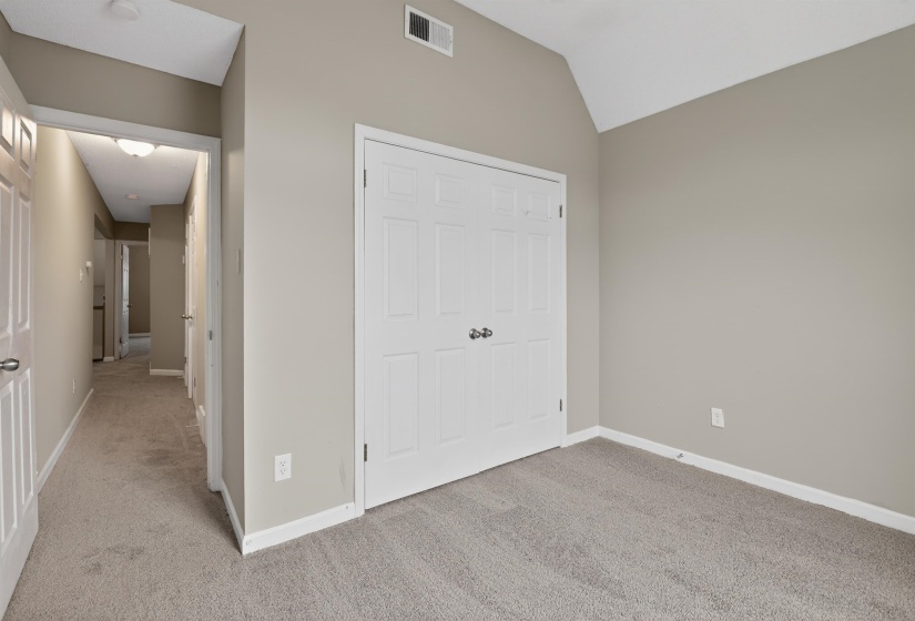 Room featuring a vaulted ceiling, neutral wall paint, and light-colored carpeting