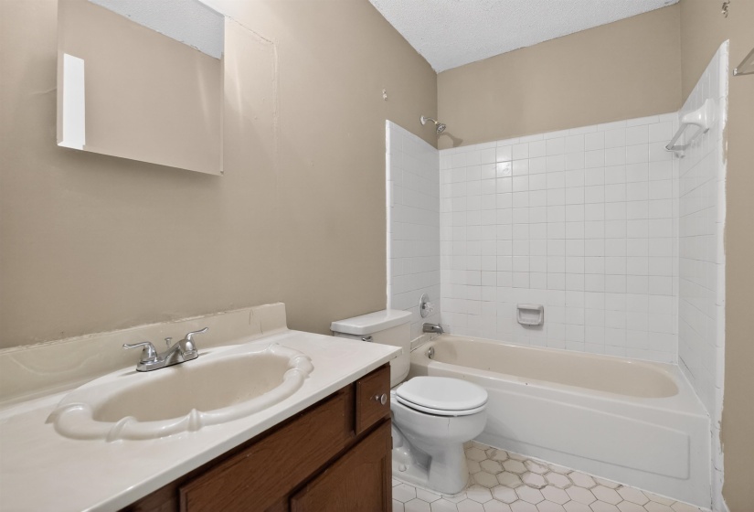 Bathroom featuring a vanity with an integrated sink, a medicine cabinet, a bathtub with white subway tile surround, and hexagonal floor tiling
