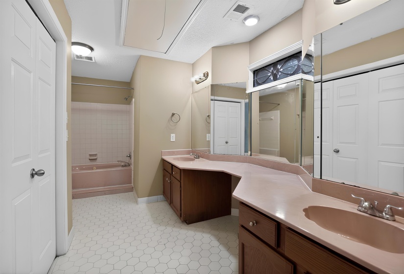 Bathroom featuring a dual vanity with integrated sinks, wood-finish cabinetry, and an expansive mirror