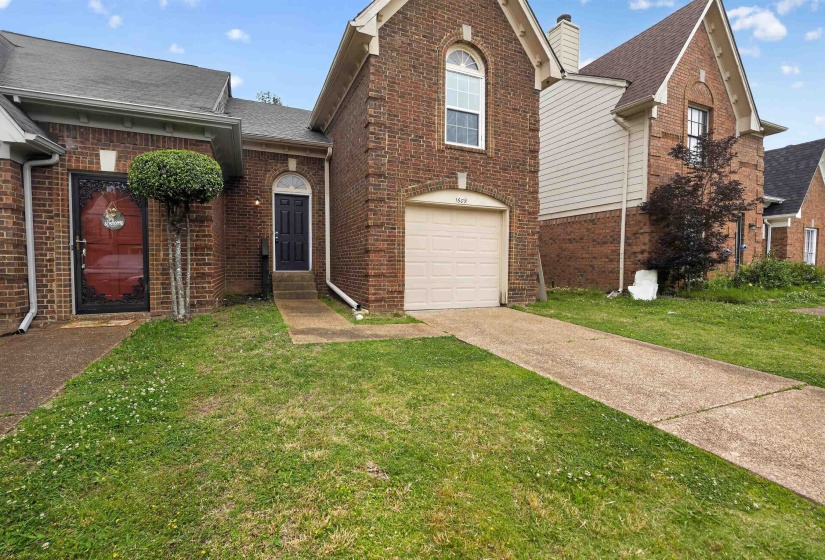 Brick exterior with a peaked roofline, an arched window, and an integrated garage