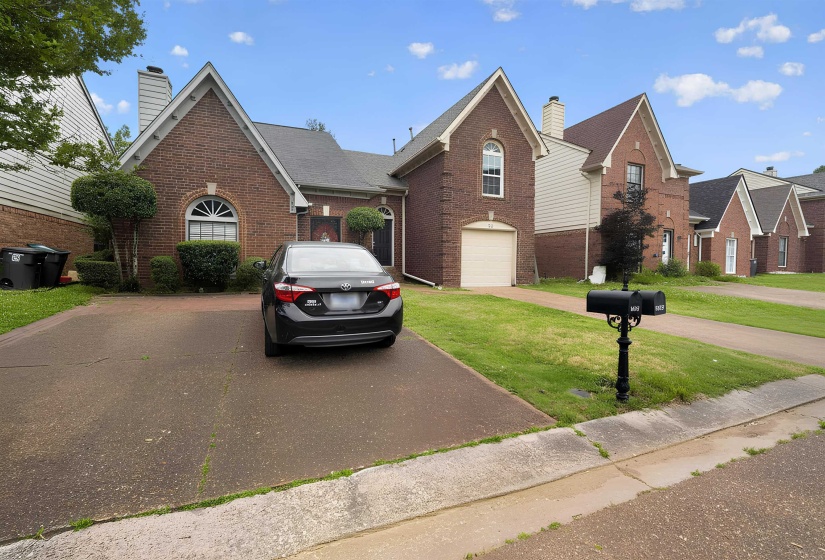 Brick facade with a gabled roofline, featuring an arched window and an attached garage