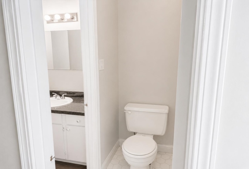 Powder room with white hexagonal tile flooring and toilet