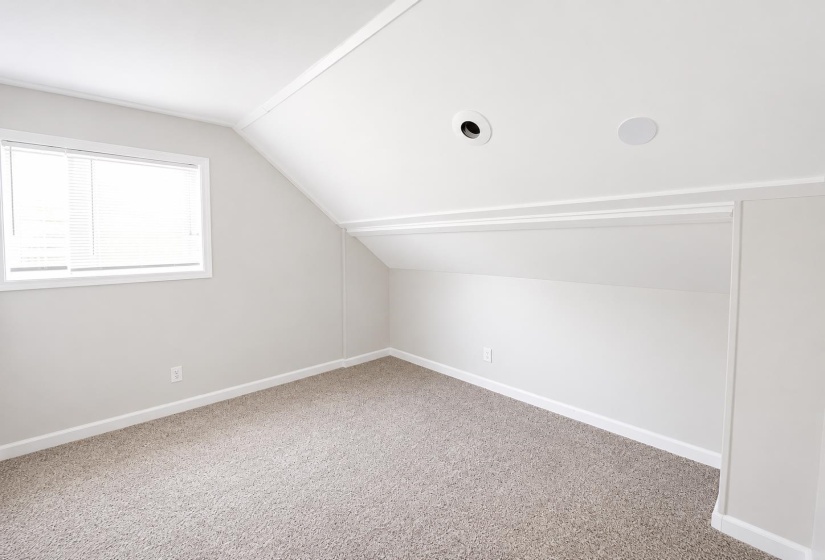 Carpeted room with a window featuring horizontal blinds