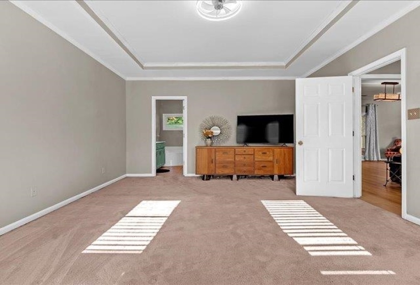 Carpeted room with a tray ceiling and crown molding