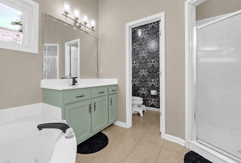 Bathroom featuring a light green vanity with a single sink and black faucet, a large mirror, and a contemporary four-light fixture