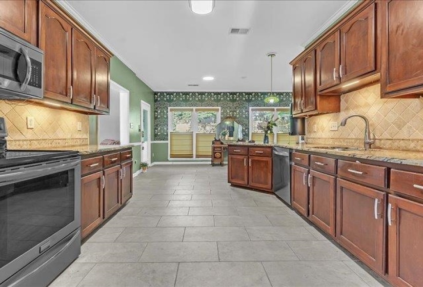 Kitchen featuring extensive wood cabinetry, stone countertops, stainless steel appliances, and tile flooring