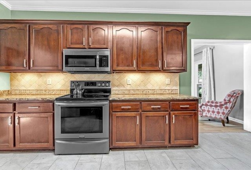 Kitchen featuring wood cabinetry, stainless steel appliances, tiled backsplash, and stone-finish countertops