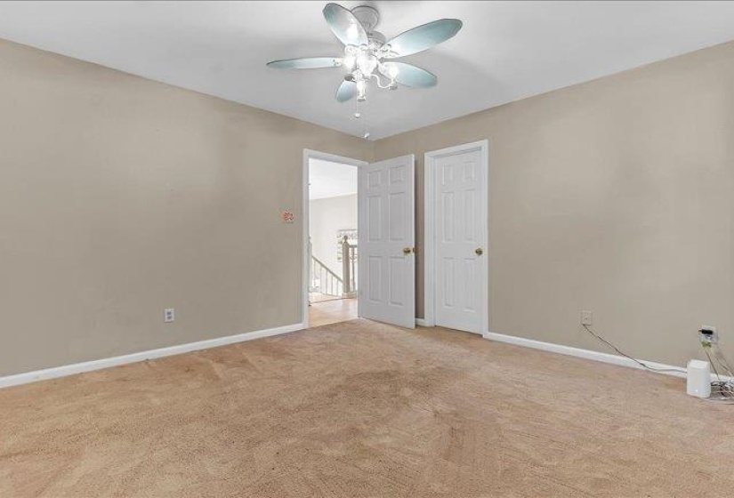 Carpeted room with a ceiling fan light fixture and neutral-toned walls