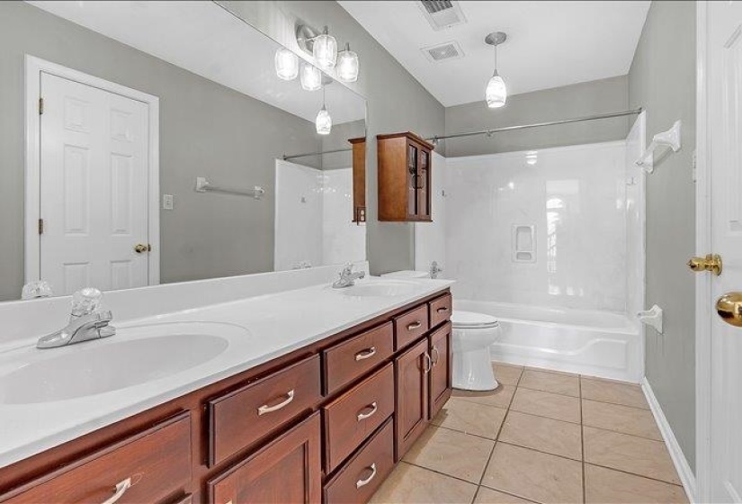 Bathroom featuring a dual vanity with a white countertop and wood-finish cabinetry