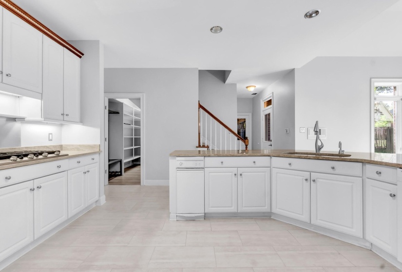 Kitchen featuring white cabinetry, light-toned countertops, a built-in sink with a gooseneck faucet, a built-in range, and tile flooring
